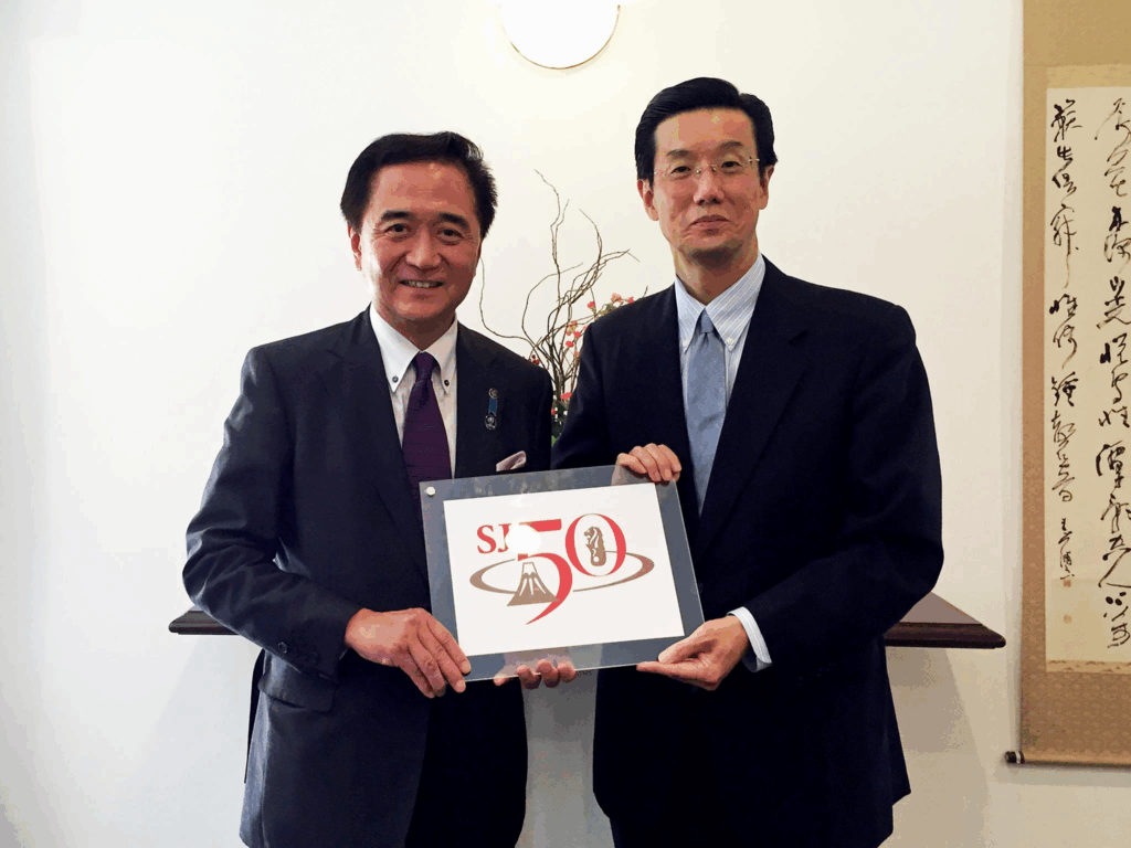 The Governor of Kanagawa Prefecture in Japan, the Honorable Yuji Kuroiwa, with H.E. Ambassador Shinoda holding the SJ50 logo in the memorandum lunch